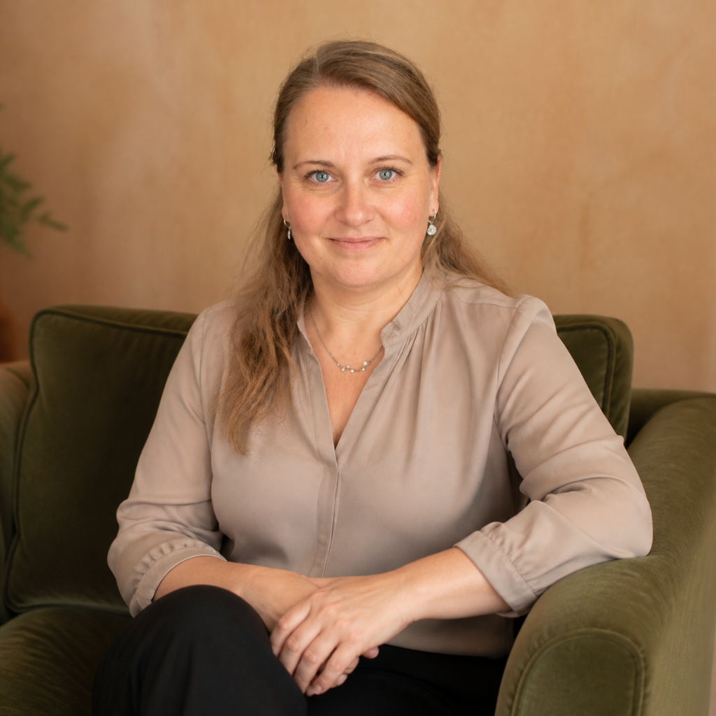 Kati Huber, systemische Beraterin, sitzt lächelnd auf einem grünen Sessel